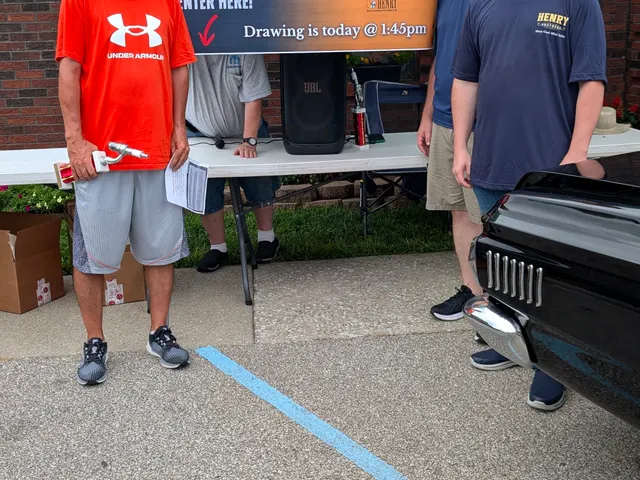 Henry Brothers team members with a car show trophy winner at their booth during a Jeffersonville, Indiana community event