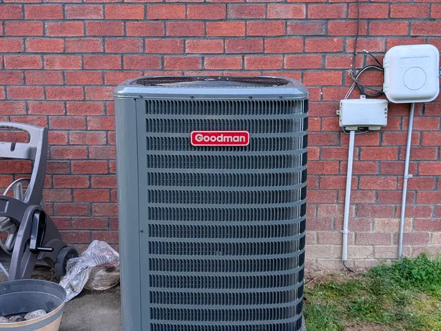 Goodman central air condenser unit installed on pad against brick exterior, Clark County Indiana