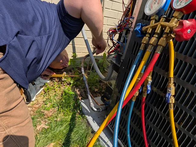 Close-up of refrigerant manifold gauge set connected to AC condenser during HVAC repair in New Albany Indiana