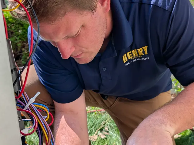 Henry Brothers branded technician brazing copper refrigerant line at outdoor AC condenser in New Albany Indiana