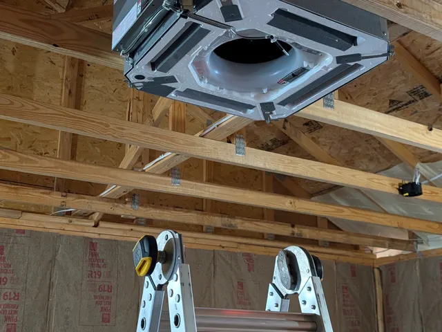 Ceiling cassette mini split unit suspended in a rough-framed outbuilding during installation