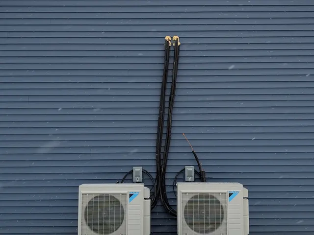 Two Daikin mini-split outdoor condenser units fully installed on pads at a new-construction building gable end in the snow
