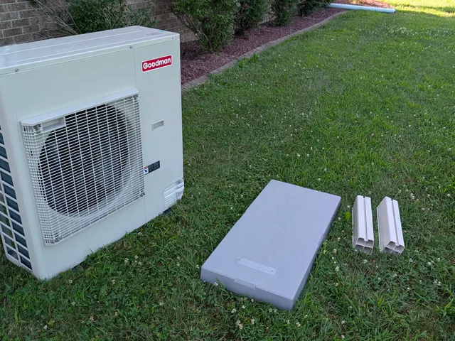 Goodman mini-split outdoor condenser staged on the lawn with composite equipment pad and lineset covers before installation, Clark County Indiana