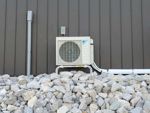Daikin mini-split condenser with line-set chase and disconnect box mounted on Indiana pole barn