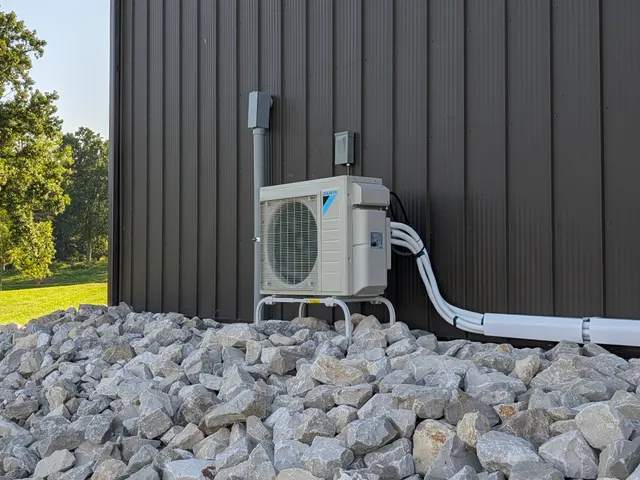Daikin mini-split outdoor condenser installed on pole barn corner with rural Indiana landscape visible
