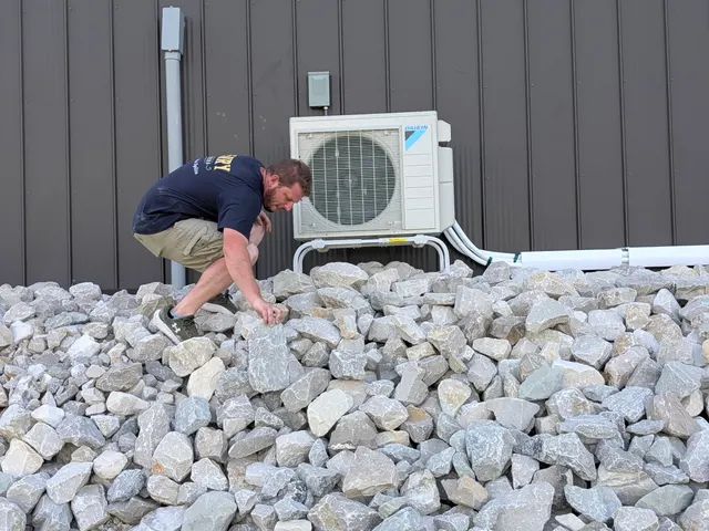 Henry Brothers technician climbing rock bed during Daikin mini-split install at Indiana barn