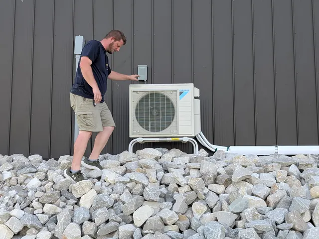 Technician beside completed Daikin mini-split outdoor unit mounted on pole barn wall Indiana