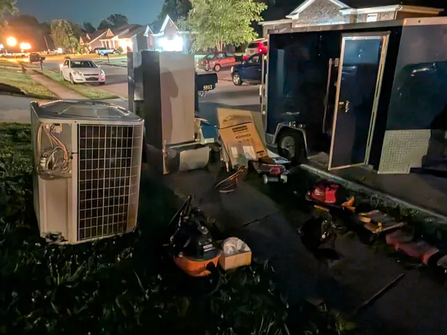 Henry Brothers work trailer and the old condenser removed during an evening system replacement in Memphis, Indiana