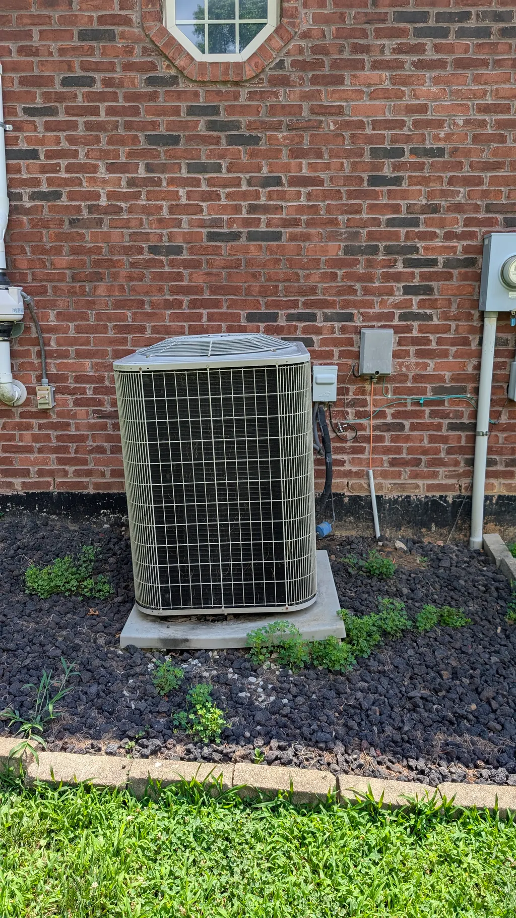Old central AC condenser unit against brick wall before removal Memphis Indiana