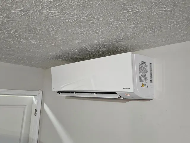 Daikin Inverter ductless indoor unit mounted high on wall near doorway with popcorn ceiling