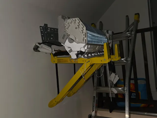 Mini-split indoor unit being positioned at high wall mount using equipment lift during installation
