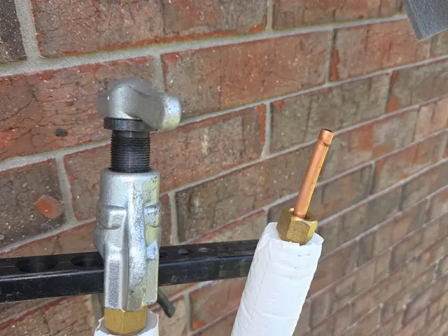 Flaring tool clamped on a mini-split copper refrigerant line to form the flare before connection at a brick exterior wall