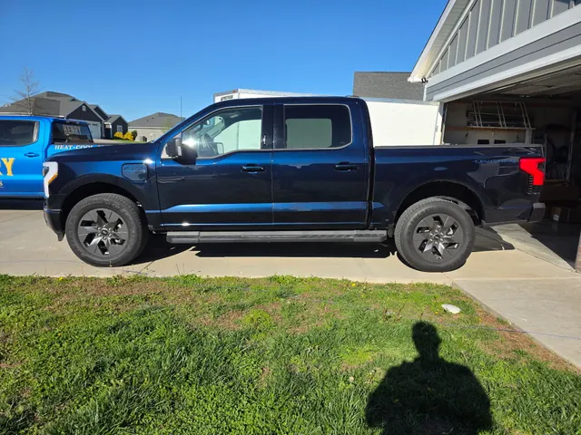 Ford F-150 Lightning electric service truck parked beside the branded Henry Brothers pickup and enclosed work trailer