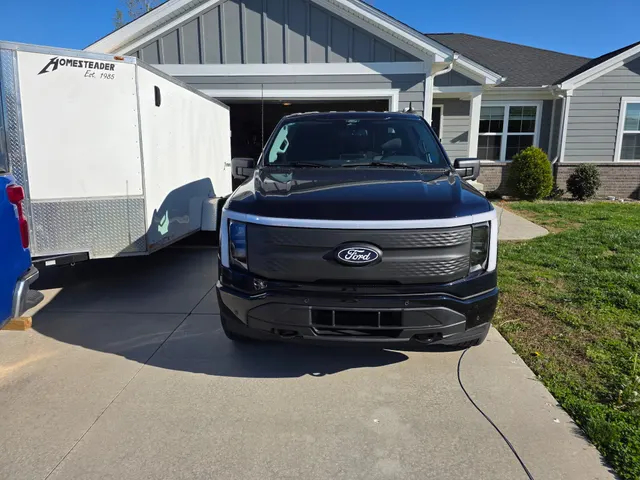 Ford F-150 Lightning electric service truck and enclosed work trailer parked in the driveway at the Henry Brothers home base